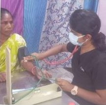 A health worker checking a woman's blood pressure at a community health camp