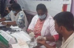 Field staff attending to community members at a health camp desk
