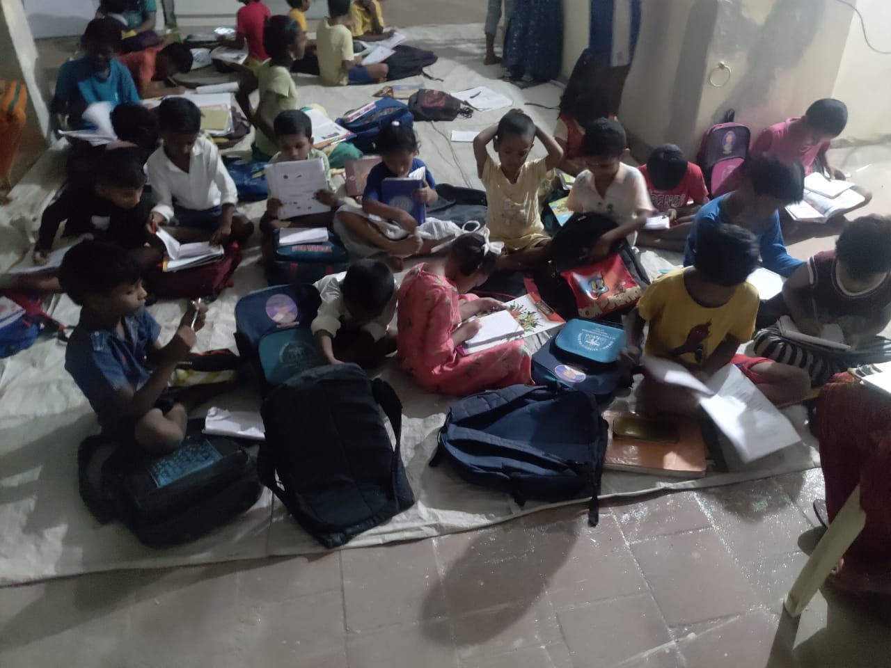 Children studying together on a mat during evening tuition